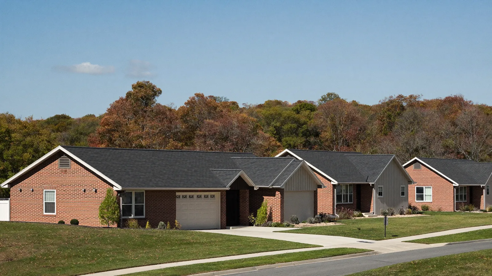Residential street of brick and vinyl homes with asphalt shingle roofs on gently rolling land in Clarksville, Tennessee, mature trees along the curb