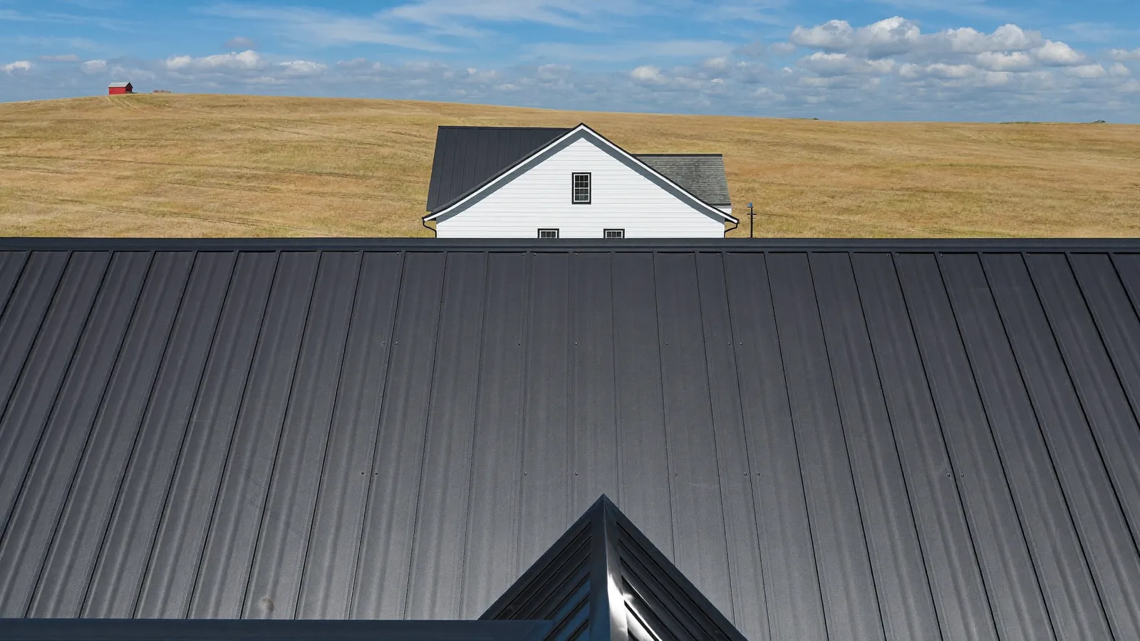 Dark standing seam metal roof with crisp vertical ribs on a farmhouse-style home on rolling land outside Clarksville, Tennessee
